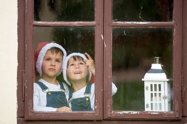 Dva roztomilý kluci, bratři, při pohledu přes okno, čekání na S — Stock fotografie