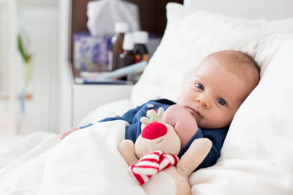 Söta nyfödda baby pojke, ligger i sängen med kallt — Stockfoto