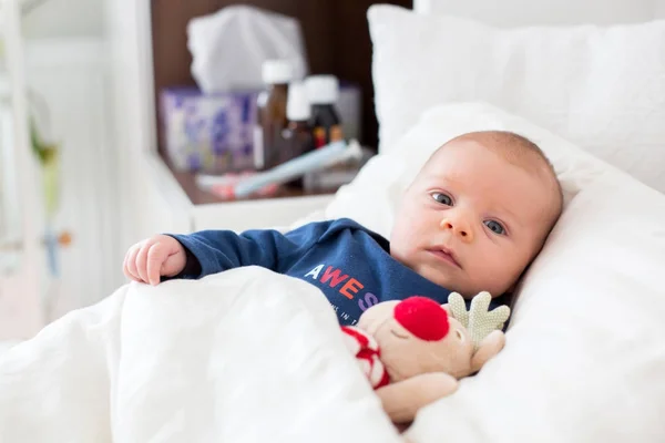 生まれたばかりのかわいい赤ちゃんの少年は、寒さでベッドで横になっています。 — ストック写真