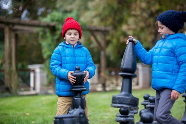 Doi copii, băieți frați, jucând șah cu figuri uriașe în t — Fotografie, imagine de stoc