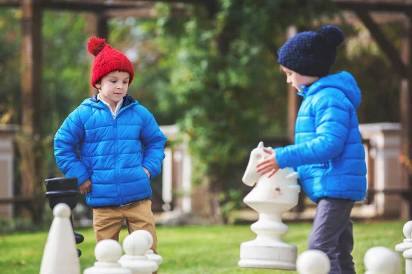 Two children, boy brothers, playing chess with huge figures in t — Stock Photo, Image