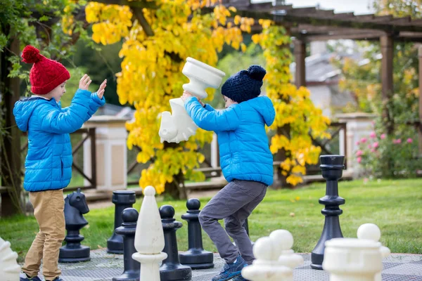 Zwei Kinder, junge Brüder, Schach spielen mit riesigen Figuren in t — Stockfoto