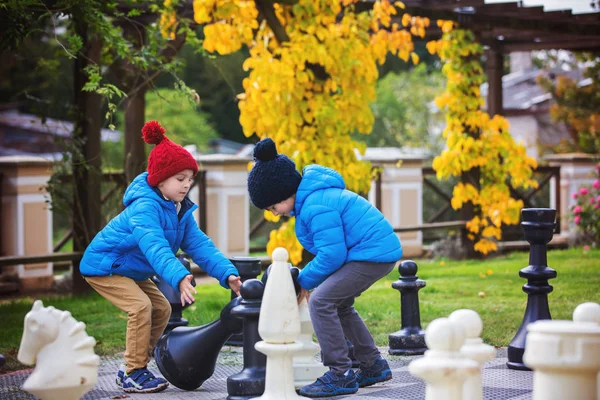 Duas crianças, meninos irmãos, jogando xadrez com grandes figuras em t — Fotografia de Stock