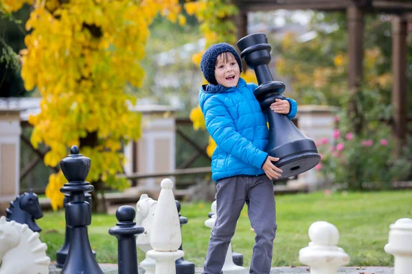 Two children, boy brothers, playing chess with huge figures in t — Stock Photo, Image