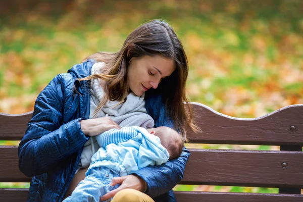 Jovem mãe, amamentando seu bebê recém-nascido menino ao ar livre no — Fotografia de Stock