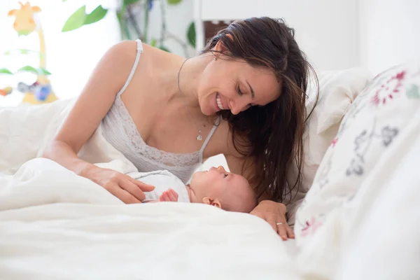 Junge Mutter, die mit ihrem Baby schläft, es in ihren Armen hält und — Stockfoto