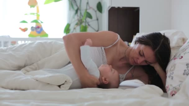 Jonge moeder borstvoeding met haar pasgeboren babyjongen in bed, dat ze hem in haar armen en lachend van geluk — Stockvideo