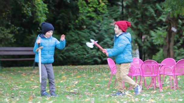 Два мальчика, играющие с мечами в парке, осеннее время — стоковое видео