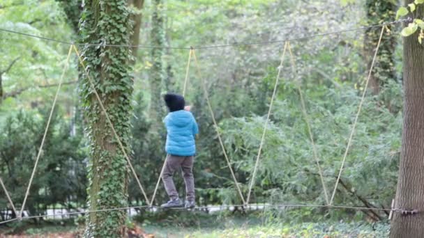 Aranyos gyerek, a fiú, hegymászó kötél játszótér struktúrában, tavasz — Stock videók