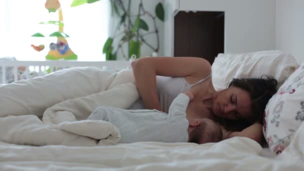 Fiatal anya a szoptatás az újszülött fiú az ágyban, tartja karjaiban és mosolyog a boldogság — Stock videók