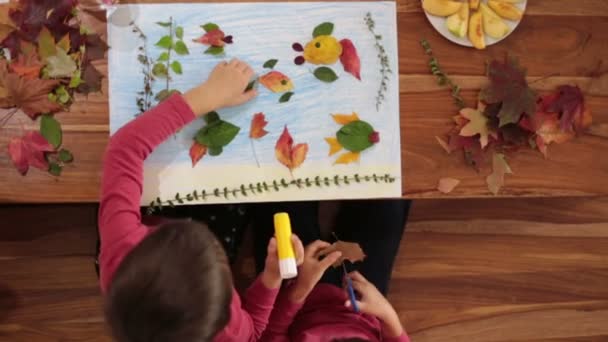 Dulces niños, niños, aplicando hojas usando pegamento mientras hacen artes y manualidades en la escuela, tiempo de otoño — Vídeos de Stock