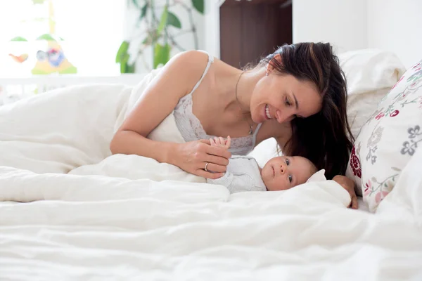 Jovem mãe dormindo com seu bebê, segurando-o em seus braços e — Fotografia de Stock