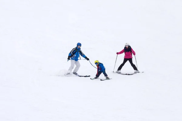 Jovem família feliz com uma criança, esquiando nas montanhas — Fotografia de Stock