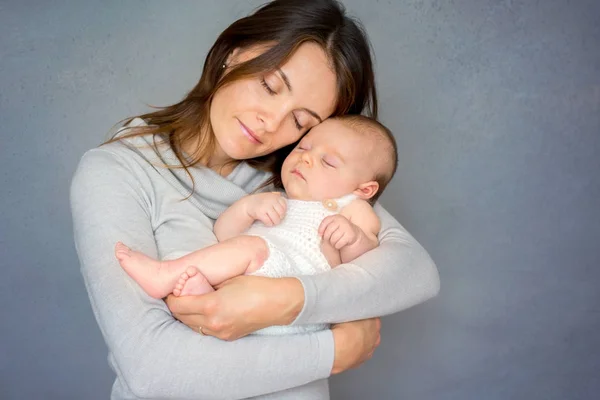 Jovem mãe, acariciando seu menino recém-nascido, segurando-o em sua — Fotografia de Stock