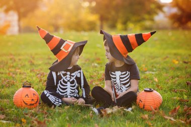 İki çocuk, çocuk kardeş Cadılar Bayramı kostümleri ile parkta