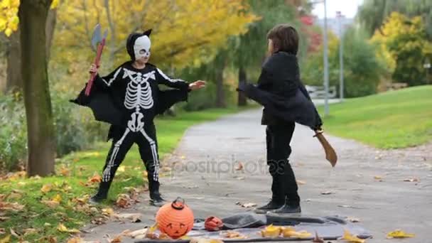 Dos niños, hermanos en el parque con disfraces de Halloween, divirtiéndose — Vídeo de stock