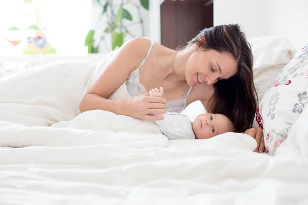 Fiatal anya gyermekét tartja a karjában a alvási és — Stock Fotó