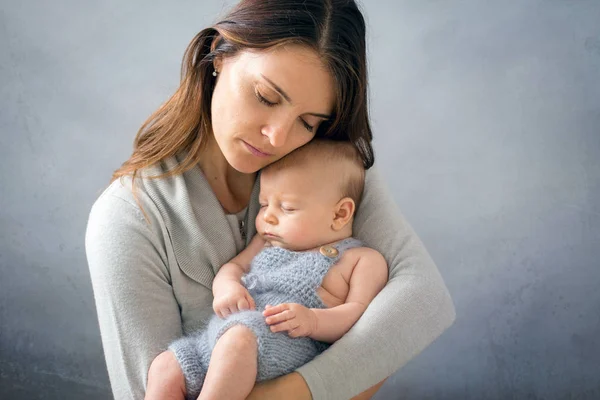 若い母親は、彼女に彼を保持彼女の生まれたばかりの赤ちゃんの男の子を caressing — ストック写真