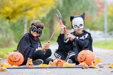 İki çocuk, çocuk kardeş Cadılar Bayramı kostümleri ile parkta