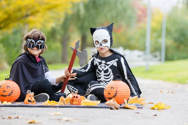 İki çocuk, çocuk kardeş Cadılar Bayramı kostümleri ile parkta