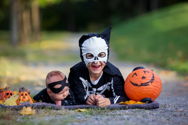 İki çocuk, çocuk kardeş Cadılar Bayramı kostümleri ile parkta