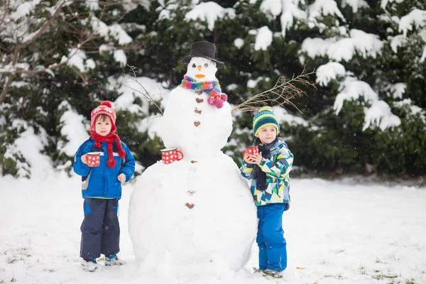 Mutlu güzel çocuklar, kardeşler, Bina kardan adam bahçe içinde bir