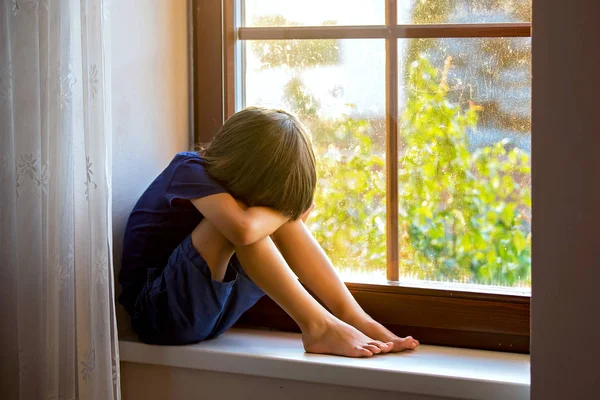 Ledsna barn, pojke, sitter på en fönster sköld — Stockfoto