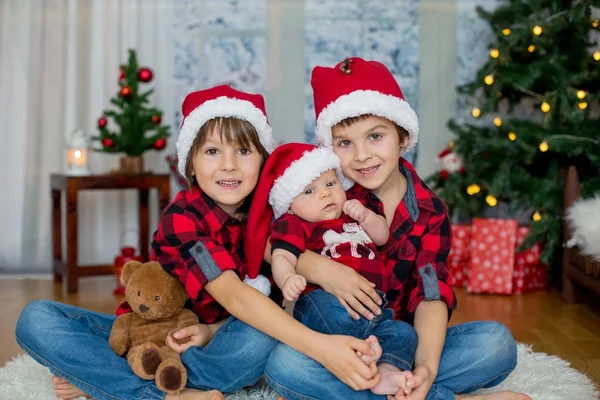 Vánoční portrét tří bratrů s Santa klobouky sedí na — Stock fotografie