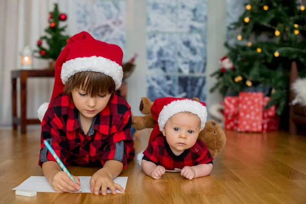 Mignon nouveau-né et son frère aîné, écrit une lettre à Santa Clau — Photo