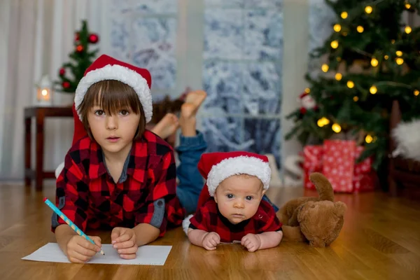 Şirin yeni doğan ve ağabeyi Santa Clau için mektup yazma, — Stok fotoğraf