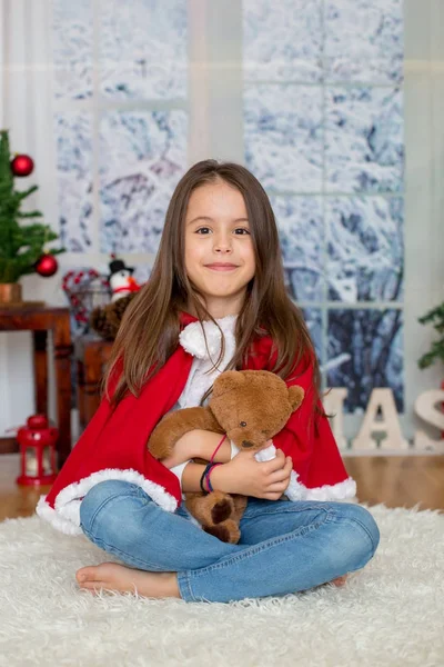 Criança feliz com brinquedo sentado na frente da árvore de Natal — Fotografia de Stock