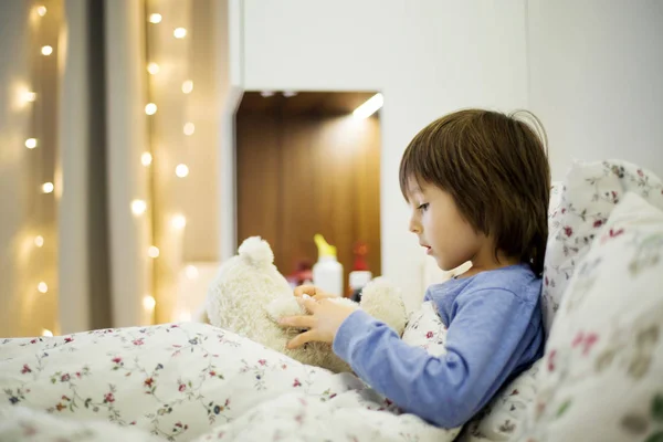 かわいい病気の子供、少年、テディベアで遊んでベッドでの滞在 — ストック写真