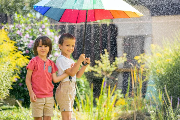 Двоє чарівних дітей, брати-хлопчики, граються з барвистими краплями — стокове фото
