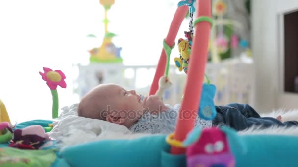 Schattige babyjongen op kleurrijke gym, spelen met speelgoed thuis, baby activiteit en play center for early infant ontwikkeling opknoping. Kinderen spelen thuis — Stockvideo