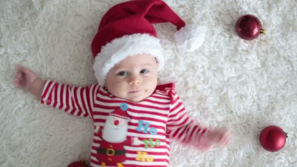 Рождественский портрет милого новорожденного мальчика, одетого в рождественскую одежду и носящего шляпу Санты, студийный снимок, зимнее время — стоковое видео