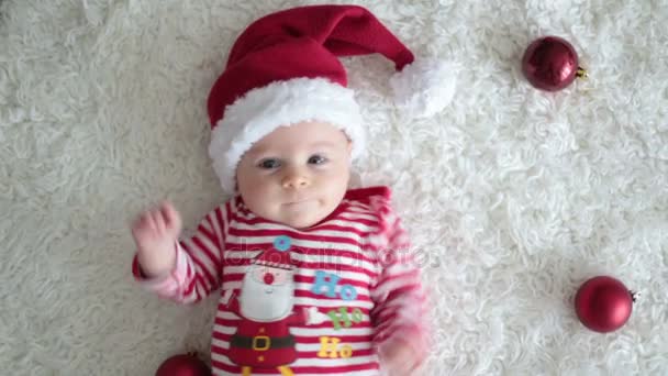 Retrato navideño de lindo bebé recién nacido, vestido con ropa navideña y con sombrero de santa, toma de estudio, tiempo de invierno — Vídeo de stock