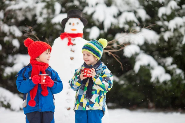Felice bella bambini, fratelli, costruzione pupazzo di neve in giardino a — Foto Stock