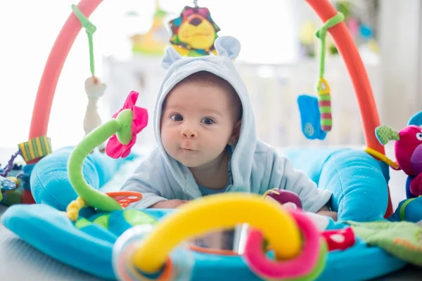 Lindo bebé en el gimnasio colorido, jugando con juguetes colgantes en casa — Foto de Stock
