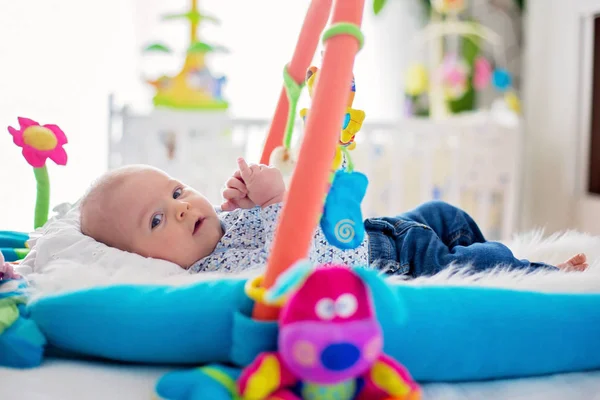 Cute baby boy on colorful gym, playing with hanging toys at home — Stock Photo, Image