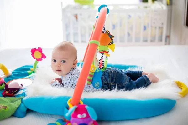 Cute baby boy on colorful gym, playing with hanging toys at home — Stock Photo, Image