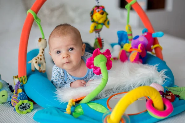 Cute baby boy on colorful gym, playing with hanging toys at home — Stock Photo, Image