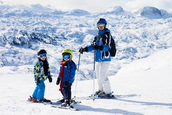 Padre y dos niños, esquiando en un día soleado en una cumbre de montaña —  Fotos de Stock