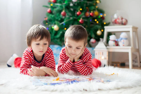 Dos chicos, leyendo un libro delante del árbol de Navidad —  Fotos de Stock