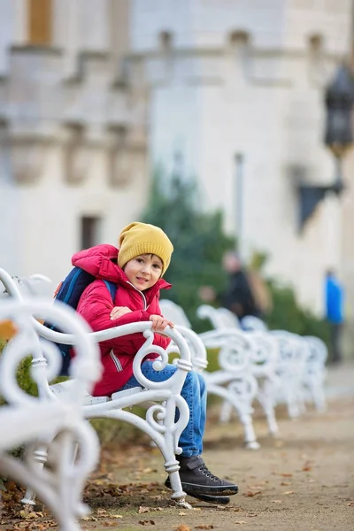 Güze önünde bir bankta oturan sevimli güzel çocuk, çocuk, — Stok fotoğraf