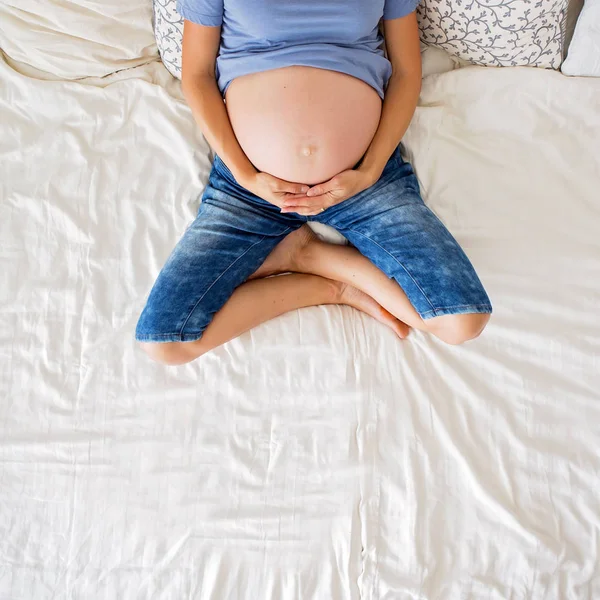 Jeune femme enceinte, couchée au lit avec tablette, livre, café et — Photo