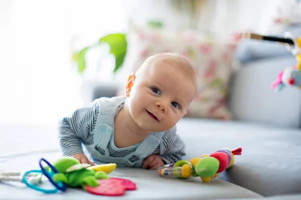 Söt baby pojke, leka med leksaker i ett soligt vardagsrum — Stockfoto
