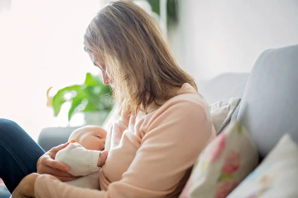 Joven madre, sosteniendo tiernamente a su bebé recién nacido — Foto de Stock