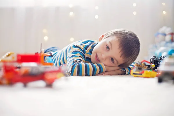 Pequeño niño jugando con un montón de juguetes de plástico de colores en interiores — Foto de Stock