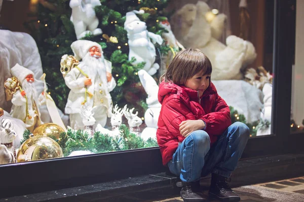 Triste niño pequeño, viendo la decoración de Navidad con juguetes en un s —  Fotos de Stock