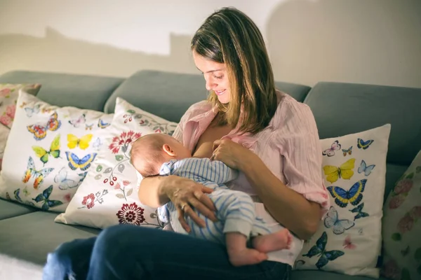 Jovem mãe bonita, amamentando seu bebê recém-nascido menino — Fotografia de Stock